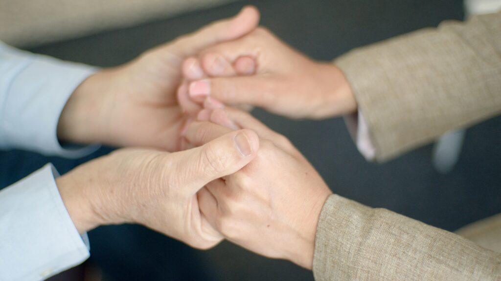 Caregiver holding elderly person's hand showing compassionate home care service"